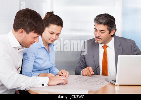 Mature Male Broker Explaining Plan To Young Couple Stock Photo