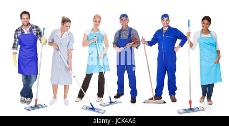 Multi Racial Group Of Cleaners Holding Mop Over White Background Stock Photo