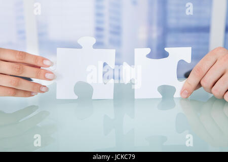 Cropped image of business people joining jigsaw pieces in office Stock Photo