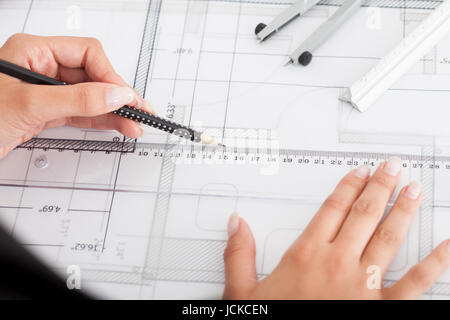 Cropped image of businesswoman working on blueprint at office Stock Photo