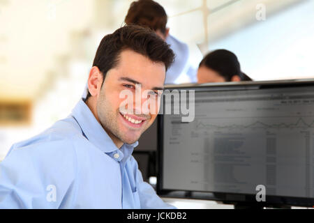 Smiling trader in front of desktop computer Stock Photo