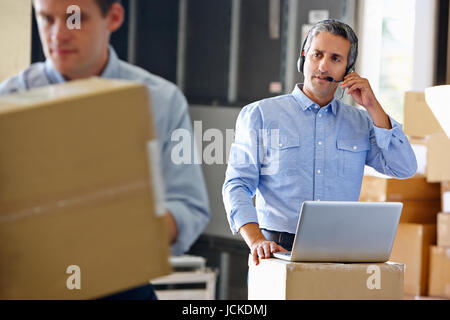 Manager Using Headset In Distribution Warehouse Stock Photo