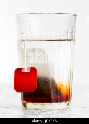 Faceted glass of boiled water and tea bag Stock Photo