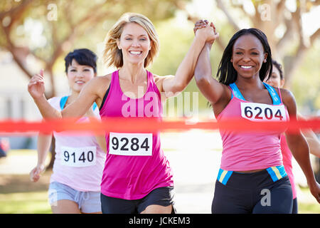 Two Female Runners Finishing Race Together Stock Photo