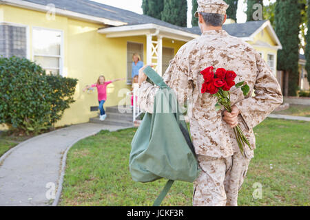 Family Welcoming Husband Home On Army Leave Stock Photo