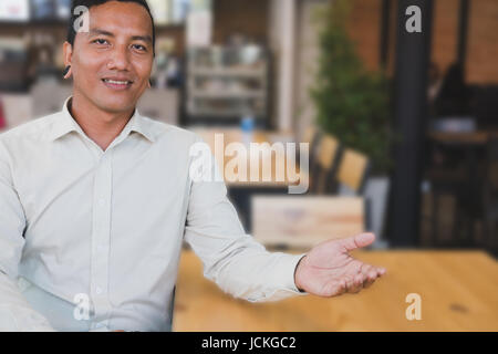 Successful small business owner sitting at his cafe coffee shop. young male entrepreneur smiling in front of his restaurant feeling confident and prou Stock Photo