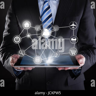 Midsection of businessman using digital tablet with various virtual icons over black background Stock Photo