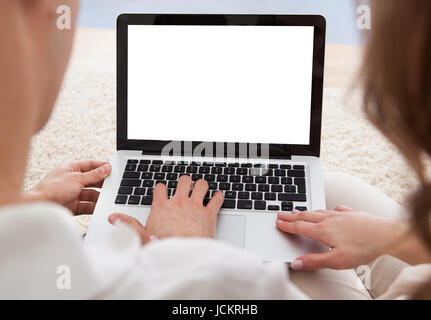 Beautiful young couple sitting side by side on a sofa looking at a laptop together Stock Photo