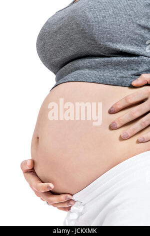 Junge frau mit Babybauch in erwartungsvoller Haltung als Nahaufnahme isoliert vor weißem Hintergrund Stock Photo