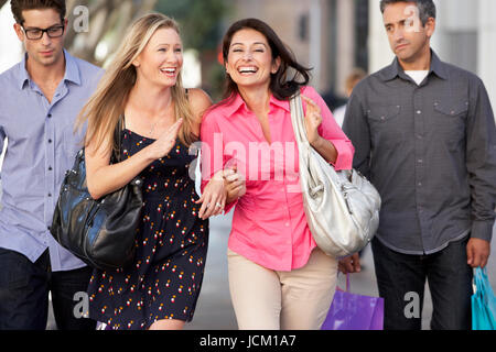 Two Couples With Bored Men Carrying Partners Bags Stock Photo