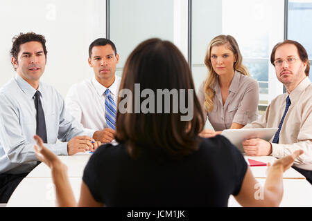 View From Behind As CEO Addresses Meeting In Boardroom Stock Photo