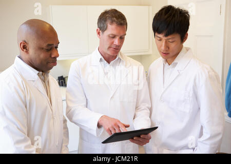 Three Doctors Having Discussion Using Digital Tablet Stock Photo