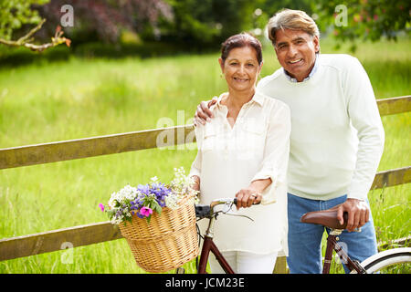 Senior Indian Couple On Cycle Ride In Countryside Stock Photo