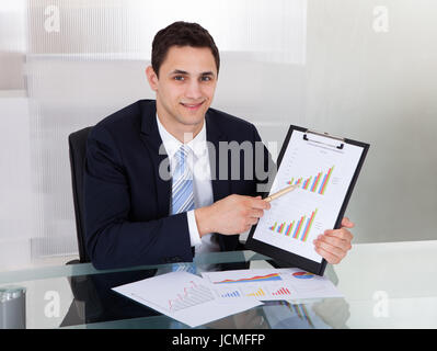 Portrait of confident businessman showing graphs at desk in office Stock Photo