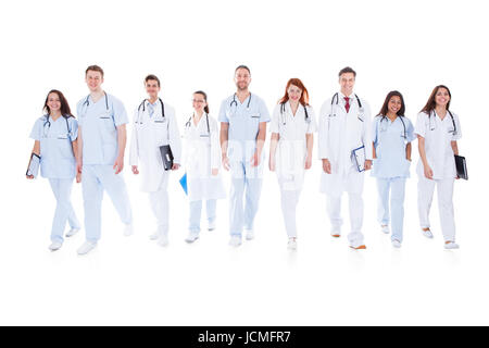 Large diverse group of doctors and nurses in uniform walking towards camera isolated on white Stock Photo