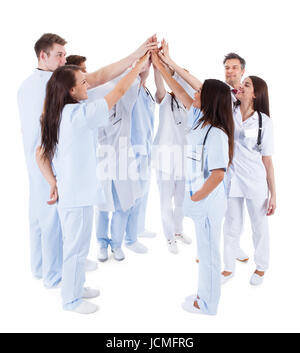 Large group of motivated doctors and nurses standing in a circle giving a high fives gesture with their hands meeting in the centre  conceptual of teamwork isolated on white Stock Photo