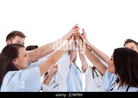 Large group of motivated doctors and nurses standing in a circle giving a high fives gesture with their hands meeting in the centre  conceptual of teamwork isolated on white Stock Photo