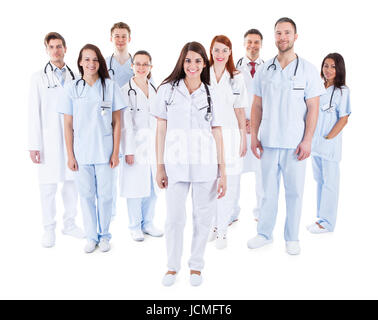 Large diverse group of medical staff in white uniforms standing grouped behind a handsome middle-aged bearded doctor or physician isolated on white Stock Photo