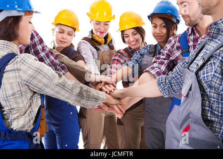 Diverse group of construction workers stacking hands. Isolated on white Stock Photo
