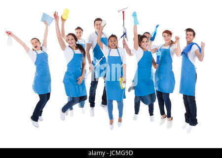 Large excited group of diverse multiethnic janitors jumping and cheering as they celebrate together as a team isolated on white Stock Photo