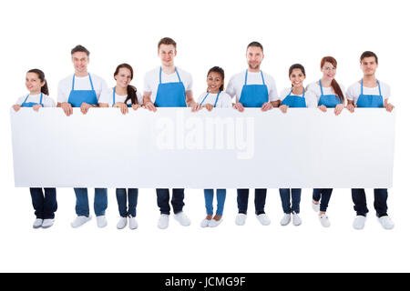 Large diverse group of cleaners or janitors wearing aprons holding a blank white banner with copy space for your text  isolated on white Stock Photo