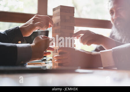 group of businessman pulling out wood building block from tower. Business strategy and planning. Stock Photo