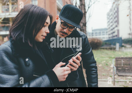 Young couple outdoor using smart phone looking screen - technology, communication, social network concept Stock Photo