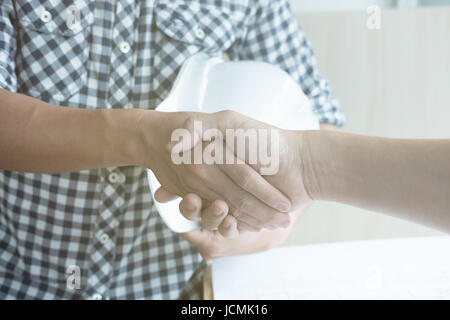 young architect and customer shaking hands at workplace. Engineer handshaking with partner for successful deal in building project development. busine Stock Photo