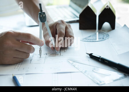 young architect working on real estate project at workplace. Engineer using divider compass at office. Male hand working with living house blueprint.  Stock Photo