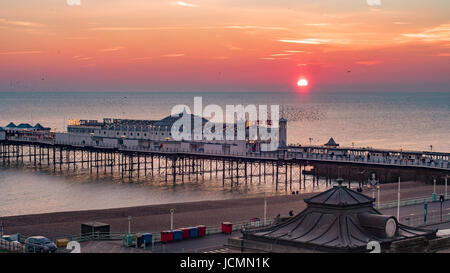 View of a sunset on  Brighton pier with a flock of birds Stock Photo