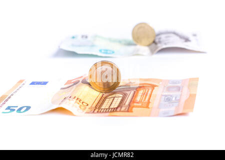 Euro notes and coins in front of British Pound notes and coins isolated on white background Stock Photo