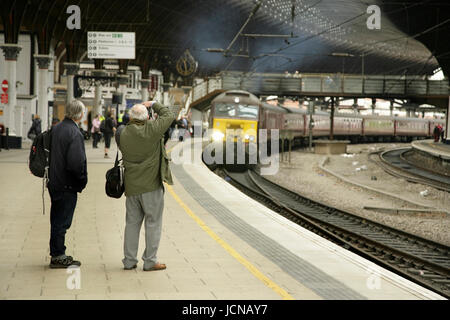 Rail enthusiasts photographing a West Coast Railways class 57 diesel loco at York station, UK