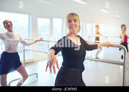 Smiling adult ballerinas standing and doing exercises in ballet class. Stock Photo