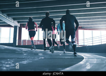Back view of sportspeople on sports ground training and running on racetrack. Stock Photo
