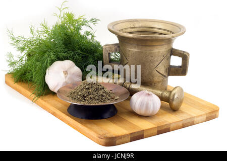 Still Life Spices, celery ,marigold staminas in a copper vase on a wooden board on a background of a stern stupa for grinding spices, bunches of dill  Stock Photo