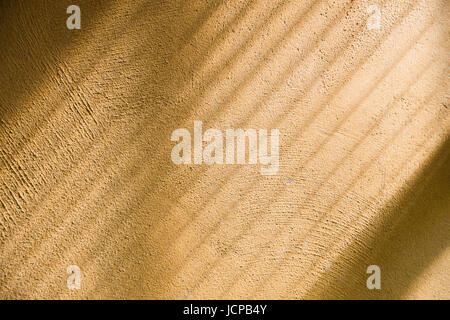 Diagonal shade and light from window curtain onto yellow rough surface wall. Stock Photo