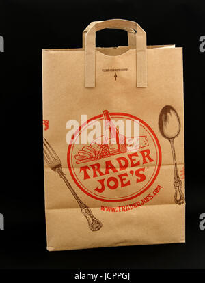 Brown paper bag from Trader Joe's grocery store stands against black background. Stock Photo