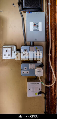 A number of 13 amp sockets mounted on a wall underneath the isolating switch Stock Photo