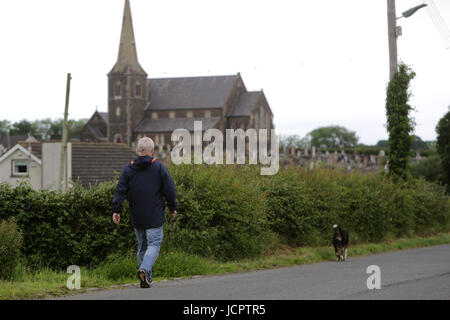 A man walks his dog down the Derryanvil Road close to Drumcree Church, Portadown 20 years since the Drumcree standoff began, Friday June 16th, 2017. The Drumcree conflict or Drumcree standoff is an ongoing dispute over yearly parades in the town of Portadown, Northern Ireland. The Orange Order (a Protestant, unionist organization) insists that it should be allowed to march its traditional route to-and-from Drumcree Church. However, most of this route is through the mainly Catholic/Irish nationalist part of town. The residents, who see the march as sectarian, triumphalist and supremacist, have  Stock Photo