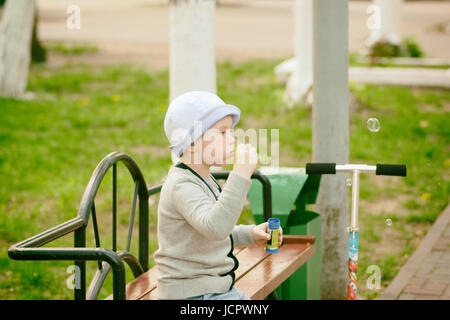 fashionable boy blowing bubbles in a city park Stock Photo