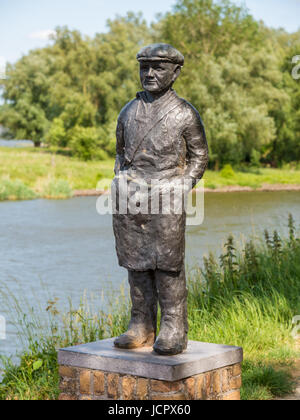 Statue of salmon fisherman on rampart of fortified town Woudrichem and river Afgedamde Maas, Netherlands Stock Photo
