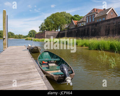 Jetty with boats on river Afgedamde Maas and city wall of old fortified town of Woudrichem, Brabant, Netherlands Stock Photo