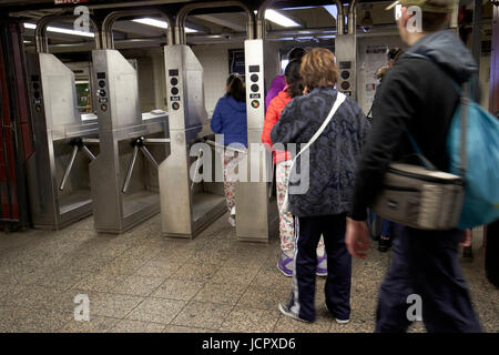 passengers moving through exit turnstiles in subway station New York City USA Stock Photo