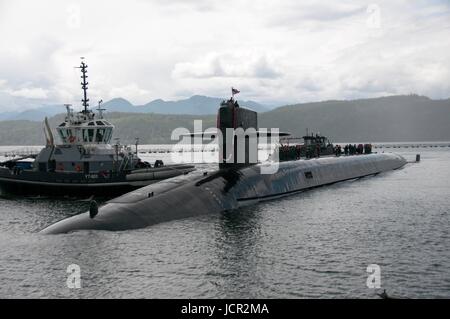 A tug boat pushes the USN Ohio-class ballistic-missile submarine USS Nebraska into dock as it returns to Naval Base Kitsap-Bangor June 9, 2017 in Bangor, Washington. Stock Photo