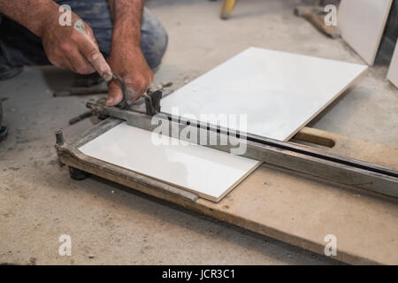 Ceramist cuts tile cutter tile, cut to an appropriate dimension, white tiles, ceramics Stock Photo
