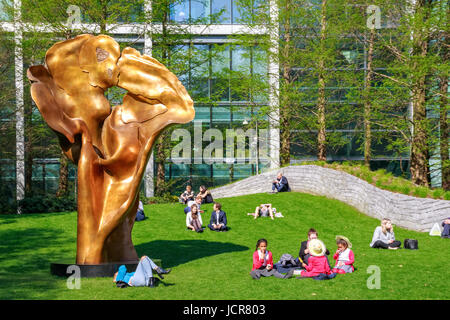 London, UK - May 10, 2017 - Fortuna, a bronze sculpture by Helaine Blumenfeld in Jubilee Park, Canary Wharf, where people are sitting and relaxing on  Stock Photo