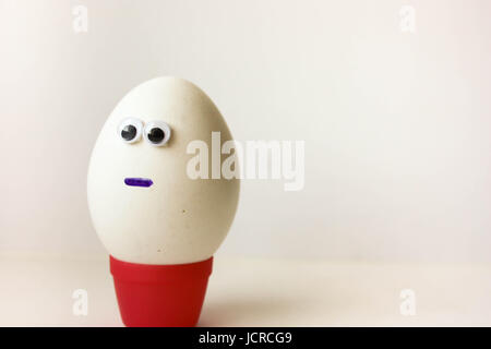 Loneliness concept. Egg with a funny painted face on a white background. Photo for your design. Stock Photo