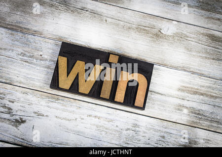 The word "win" written in wooden letterpress type on a white washed old wooden boards background. Stock Photo