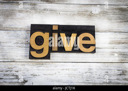 The word "give" written in wooden letterpress type on a white washed old wooden boards background. Stock Photo