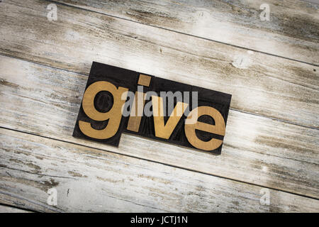 The word "give" written in wooden letterpress type on a white washed old wooden boards background. Stock Photo